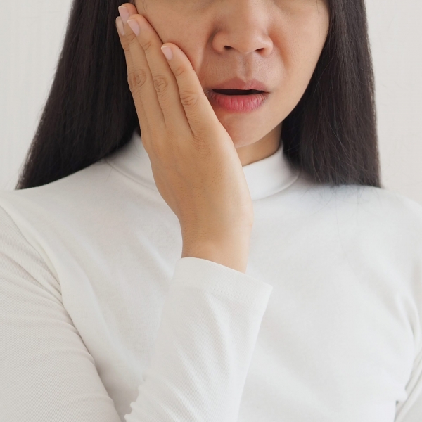 trigeminal neuralgia and temporomandibular joint and muscle disorder in asian woman, She uses hand touching her cheek and symptoms fo pain and suffering on isolated white background.