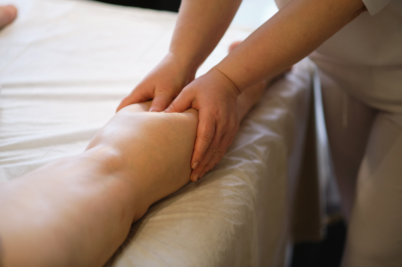 Detail of hands massaging human calf muscle.Therapist applying pressure on female leg. Hands of massage therapist massaging legs of young woman in spa salon. Body care in spa salon for young woman